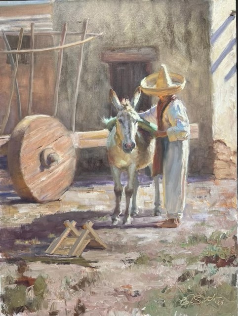 Man wearing a broad-brimmed hat standing beside a burro in a sunlit adobe courtyard